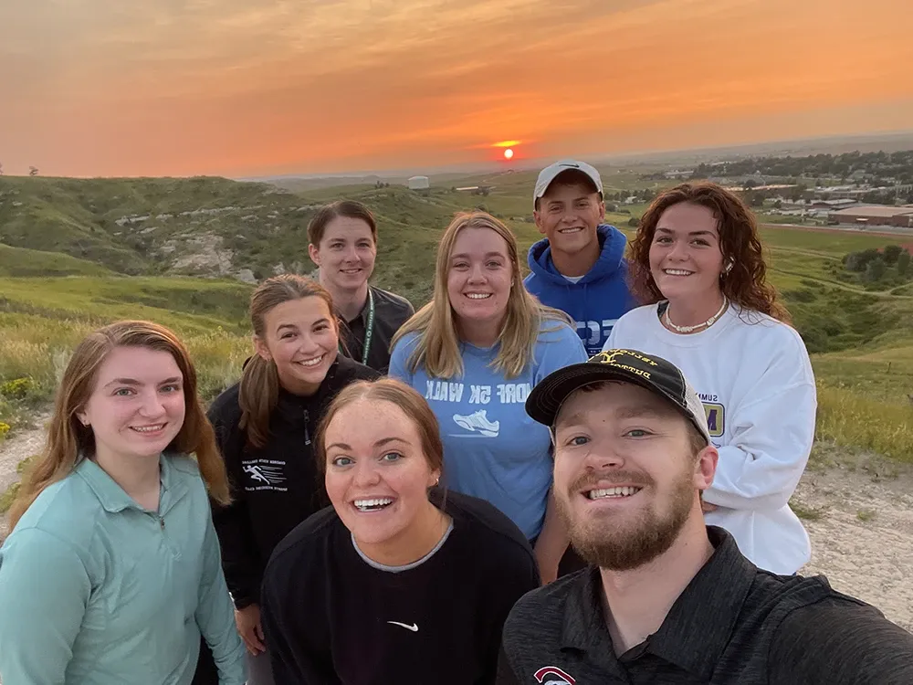 A group of students smiling at the camera at sunrise